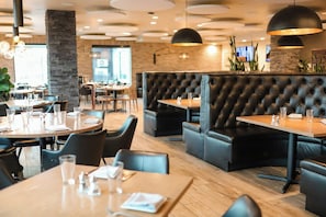 A restaurant interior with round tables, black leather booths, and pendant lighting. - Black Rock Mountain Resort (Heber City)
