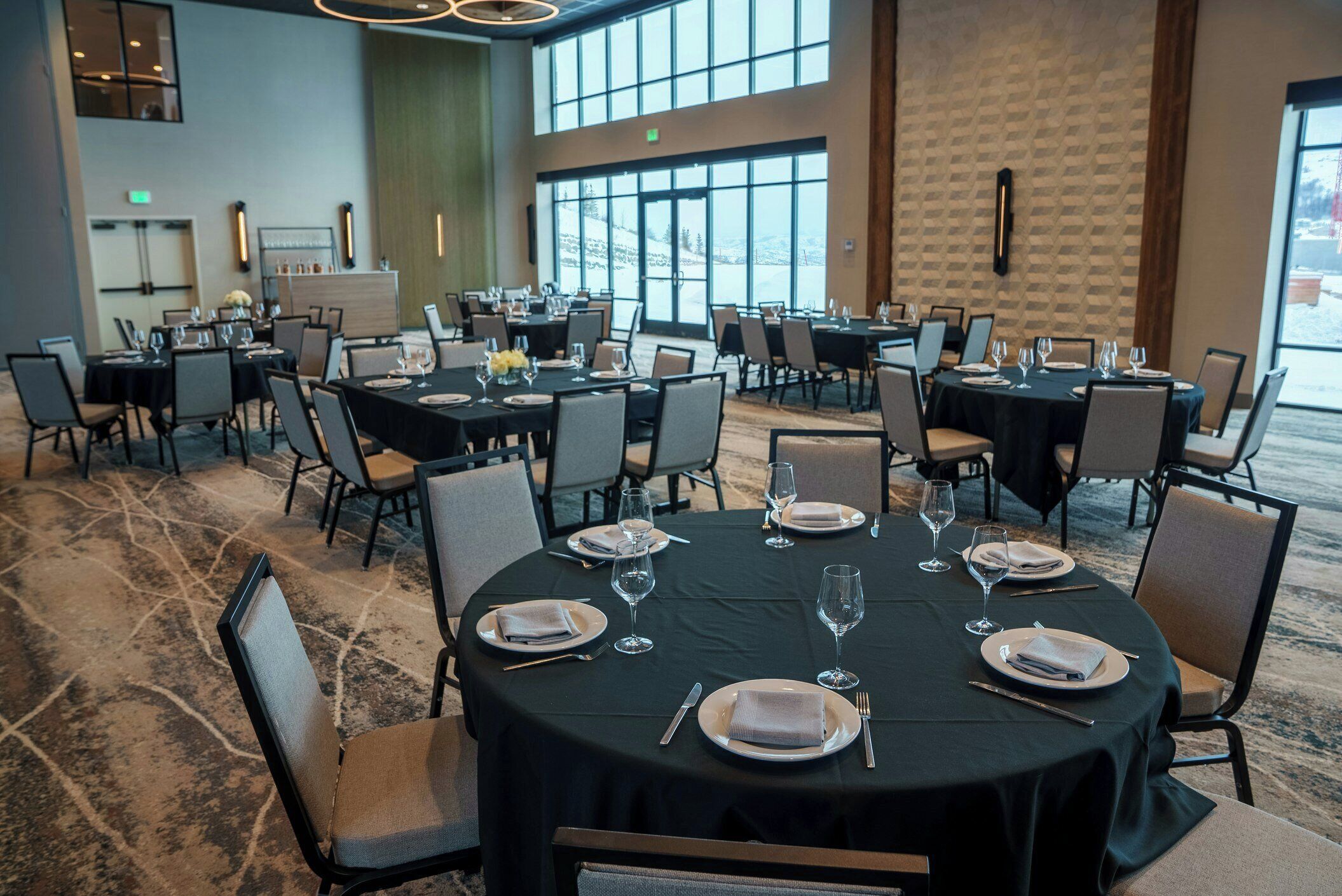 Un salón de conferencias con varias mesas dispuestas para comer, equipado con sillas y mantelería.