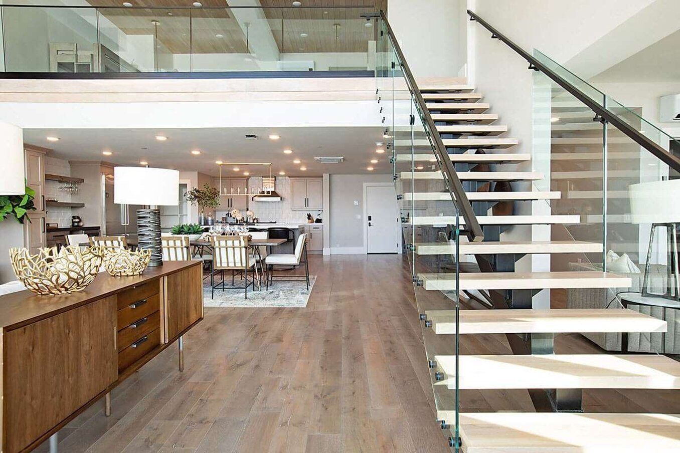 Ein modernes Interieur mit Treppe, Küche, Essbereich und einer Glastrennwand.