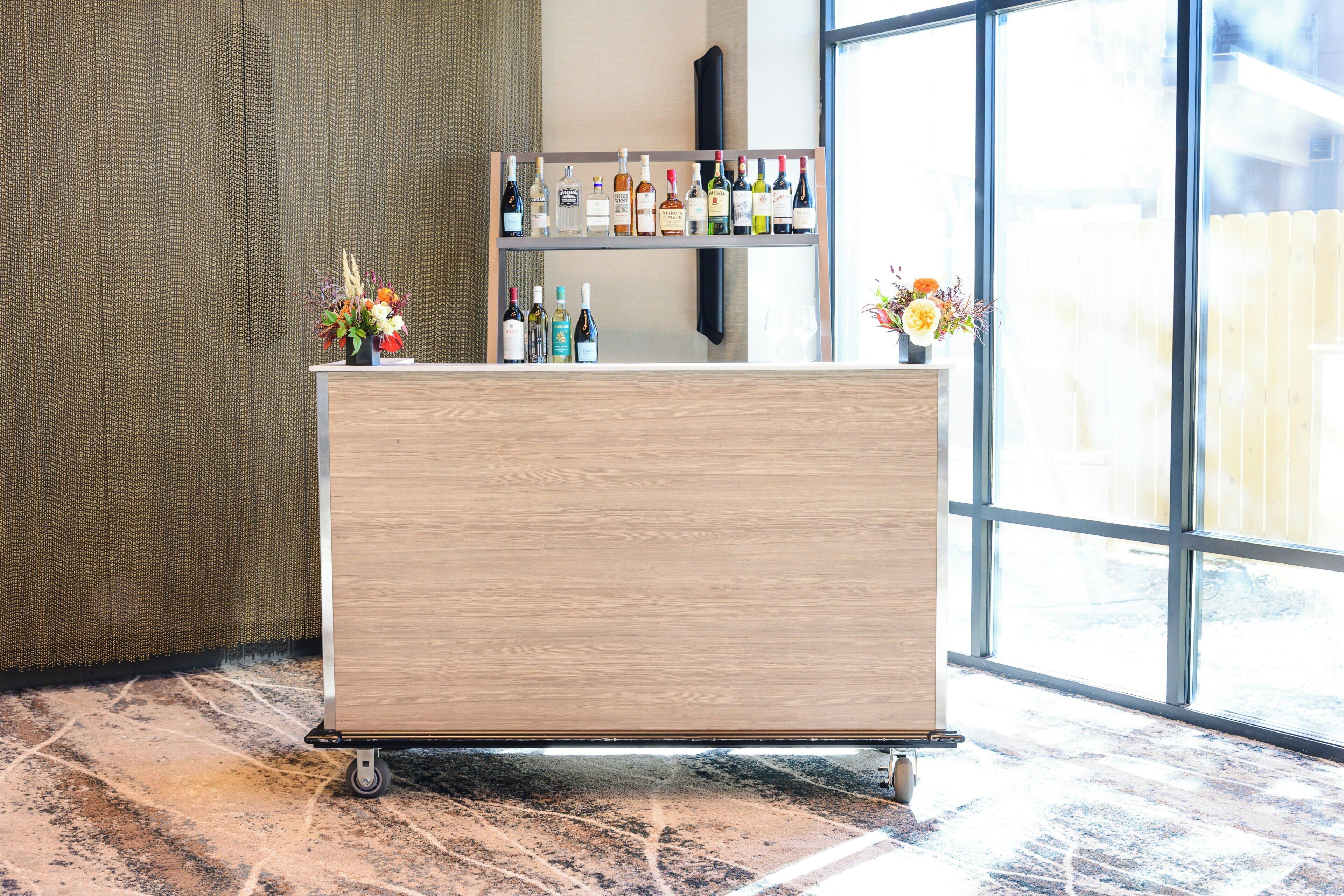 A reception area with a wooden counter, a selection of bottled beverages, and a window with a view.
