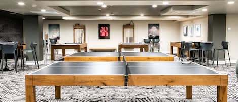Una sala de conferencias moderna con mesa de ping-pong, varias sillas y una alfombra estampada.