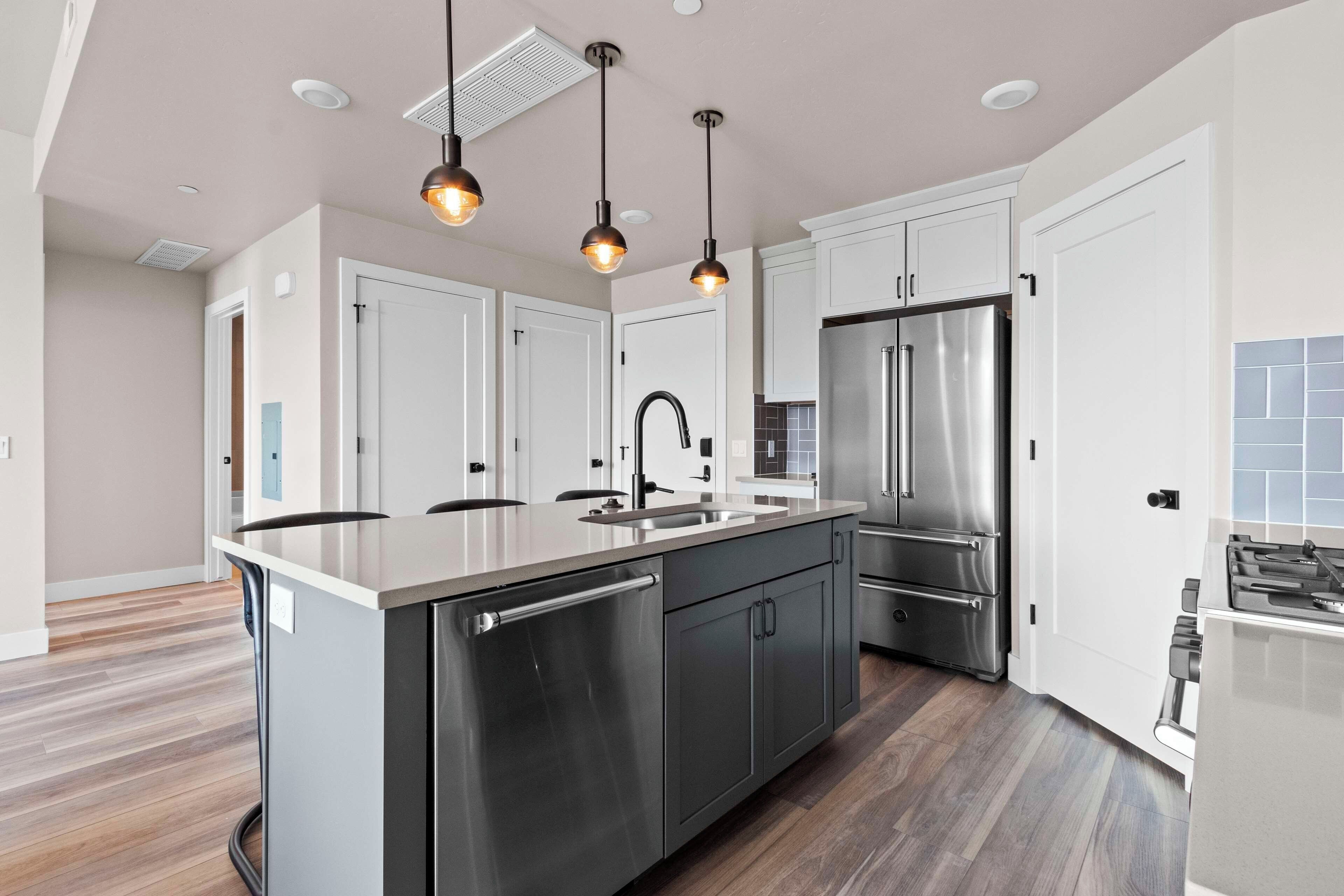 A modern kitchen with stainless steel appliances, a central island with seating, and pendant lighting.