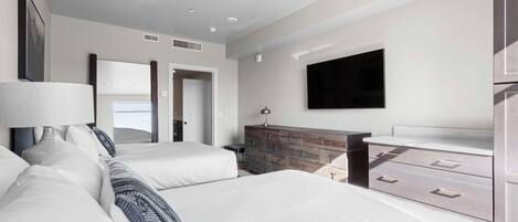 Habitación de hotel con dos camas, un aparador, un televisor de pantalla plana y un ventanal grande.