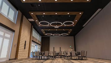 A conference room with a high ceiling, recessed lighting, and a patterned carpet.