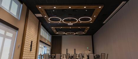A conference room with a high ceiling, recessed lighting, and a patterned carpet.