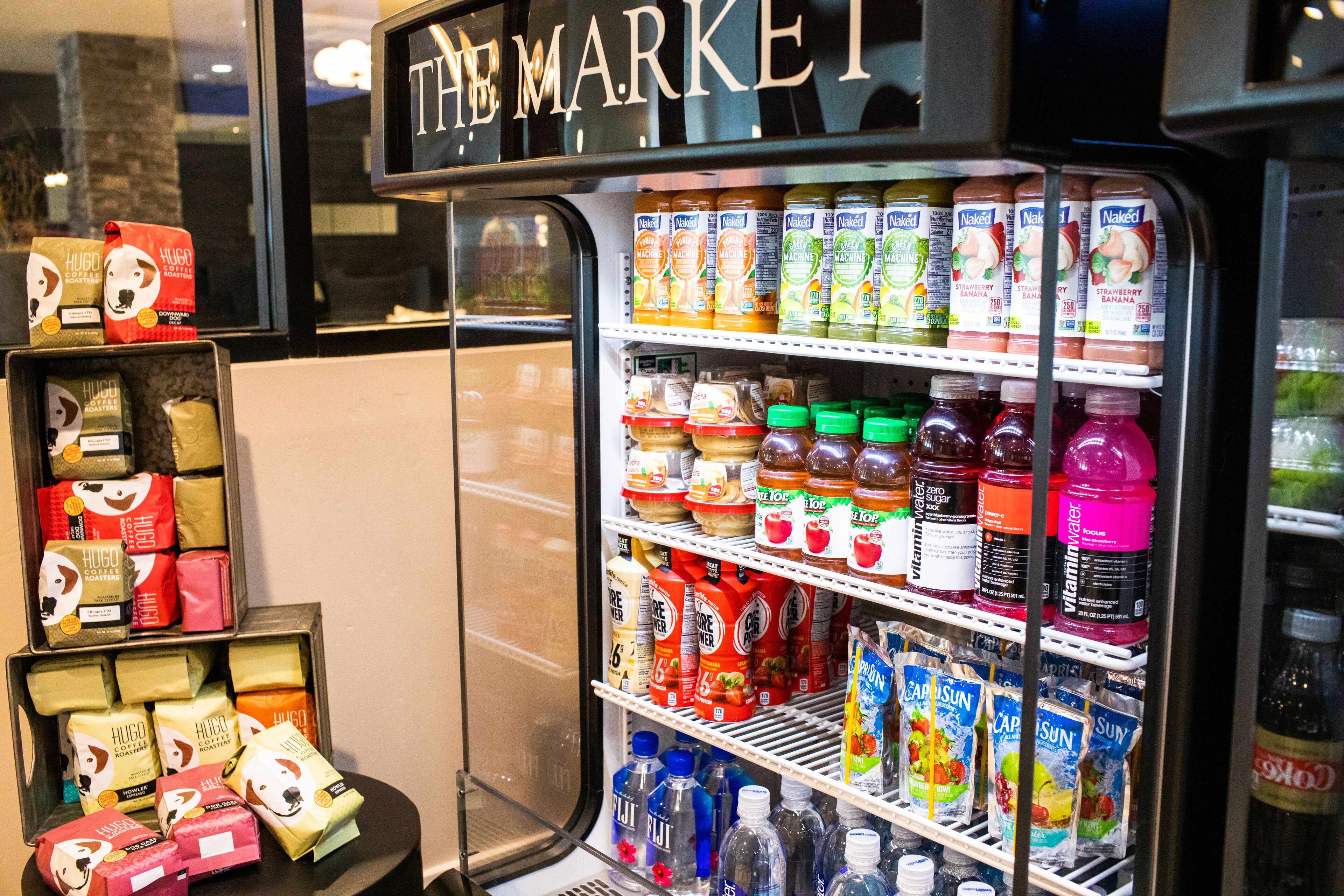 A vending machine stocked with various beverages and snacks, including Hugo brand products and CapSun juice.