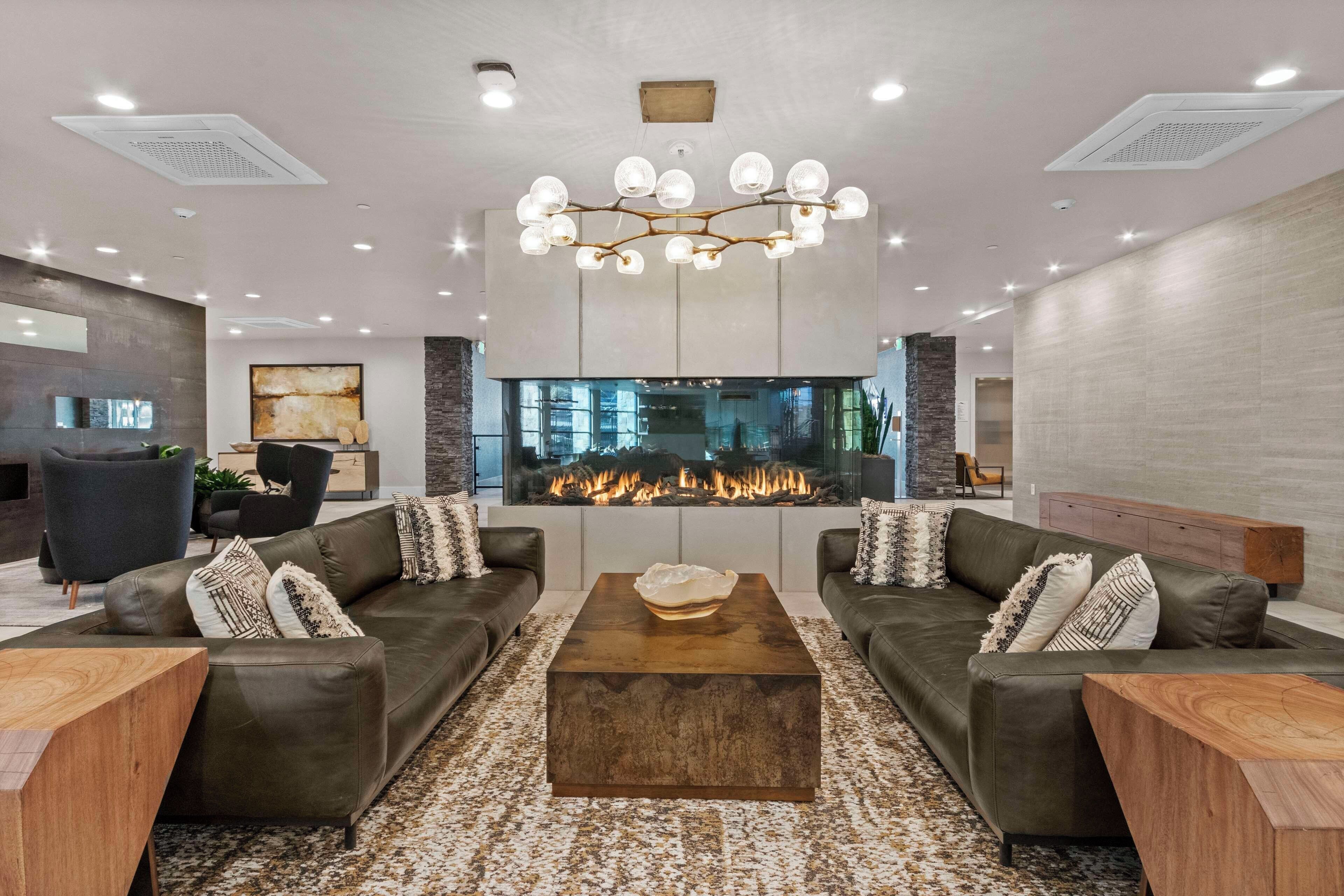 A modern living room with a fireplace, leather sofas, and a coffee table.
