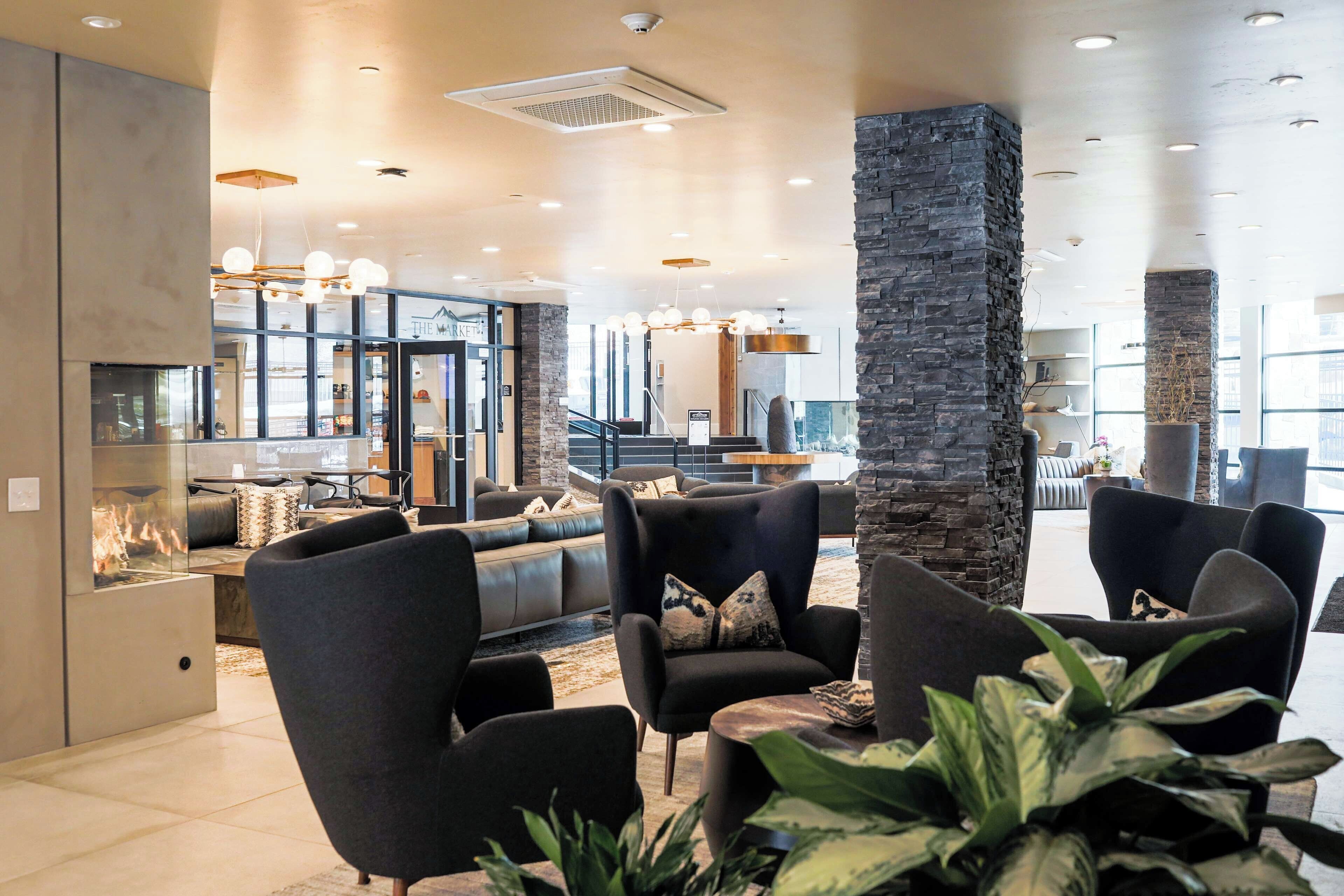 Een moderne lounge met leren banken, een stenen zuil en uitzicht op de markt door grote ramen.