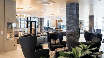 Een moderne lounge met leren banken, een stenen zuil en uitzicht op de markt door grote ramen.