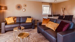 Een moderne woonkamer met twee banken, een salontafel en een eethoek met een tafel en stoelen.