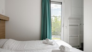 A hotel room with a bed, a window with curtains, and a white radiator.