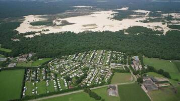 An aerial view of a residential area with organized housing, green spaces, and a large body of water in the background.