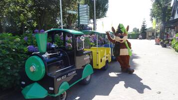 Un personaje publicitario al lado de un tren verde y negro con un número de teléfono visible.