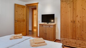 A hotel room with two beds, a television, wooden wardrobes, and a hallway. - Apartment in Grossarl Near Ski Slopes (Grossarl)