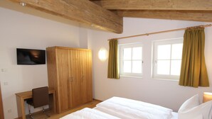 A bedroom with a wooden ceiling, a bed with white bedding, a desk with a chair, a wardrobe, and two windows with curtains. - Luxury Chalet in Saalbach-Hinterglemm near Ski Area (Saalbach-Hinterglemm)