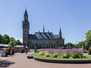 A historic building with a clock tower and a central courtyard with flowers. - Luxury Penthouse Apartment With Roof Terrace at the Harbor of Scheveningen (The Hague)