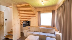 A wooden interior with a sofa, a TV, and a wooden table. - Deluxe Chalet With Whirlpool (Sankt Georgen am Kreischberg)