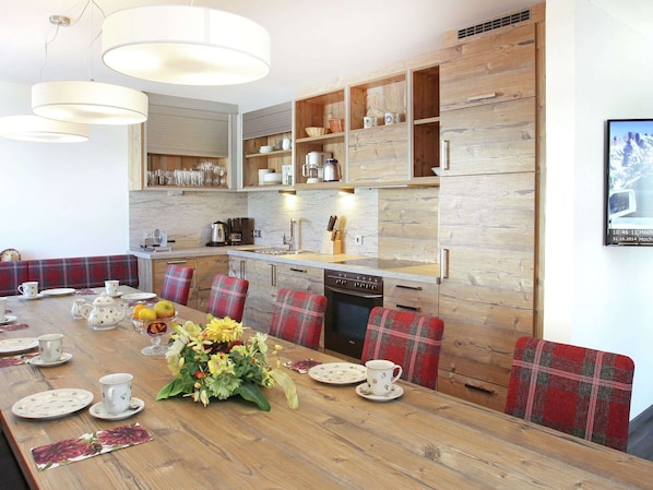 A modern kitchen with wooden cabinetry, a dining table set with tea cups and plates, and a large floral centerpiece.