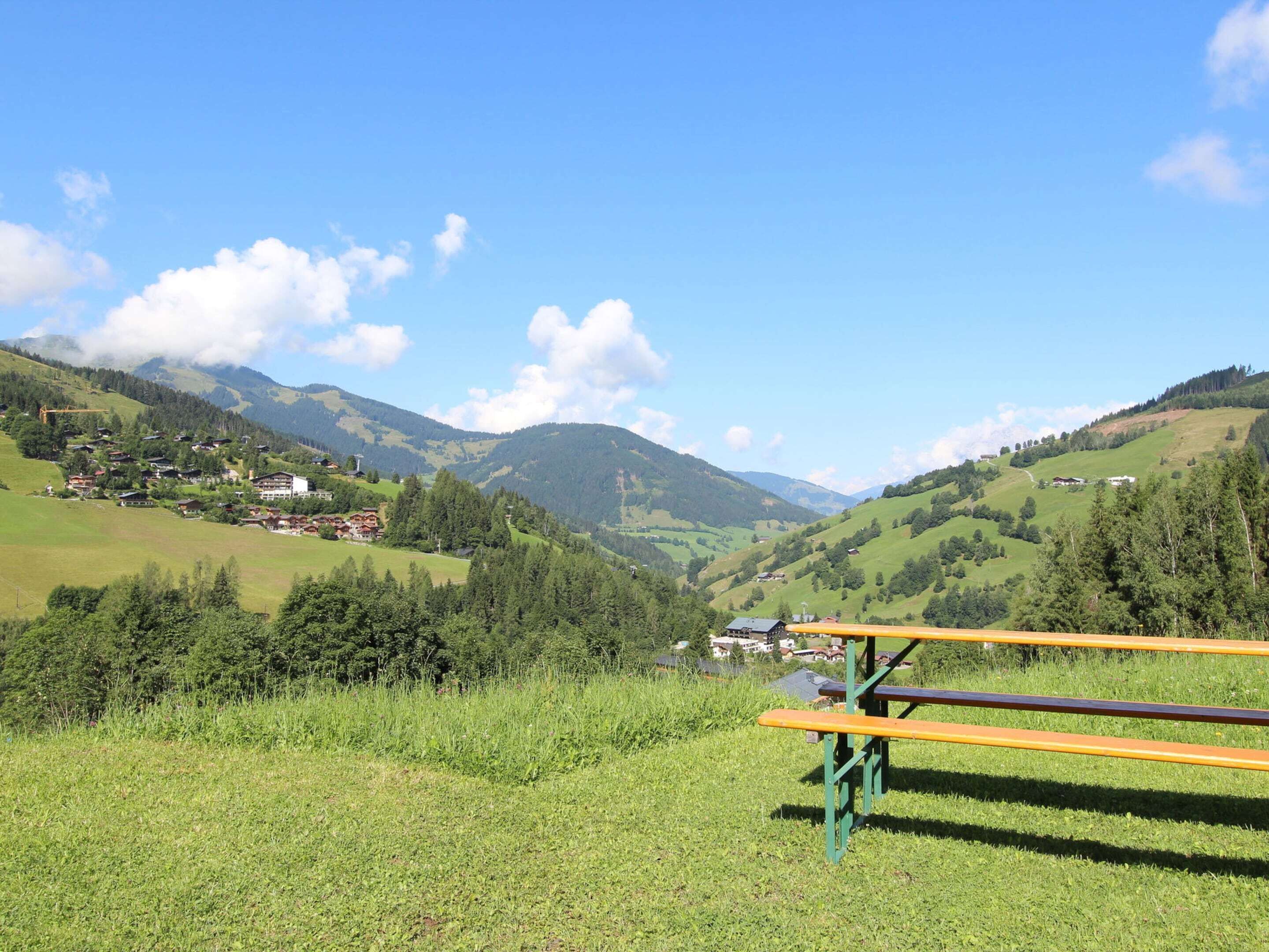Ein Picknicktisch in einem grasbewachsen Feld mit Blick auf ein Tal und Berge im Hintergrund.