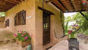 A rustic building with a wooden door, a window with shutters, and a sign above the door. - Cottage in Vezere Valley Near Lascaux Caves (Les Eyzies)