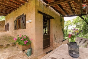 A rustic building with a wooden door, a window with shutters, and a sign above the door. - Cottage in Vezere Valley Near Lascaux Caves (Les Eyzies)