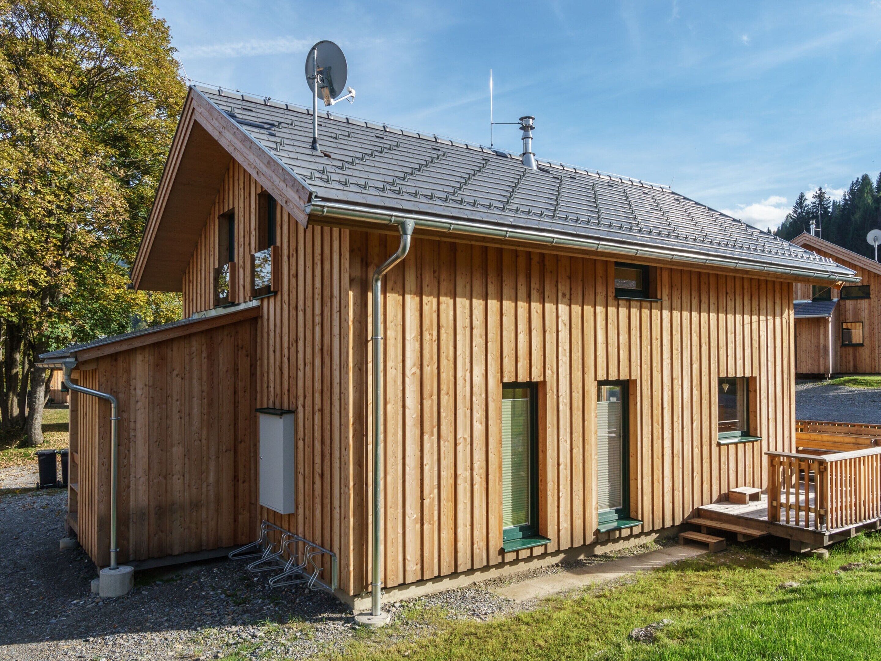 Une cabane en bois avec un toit en pente, une antenne parabolique et une petite terrasse.