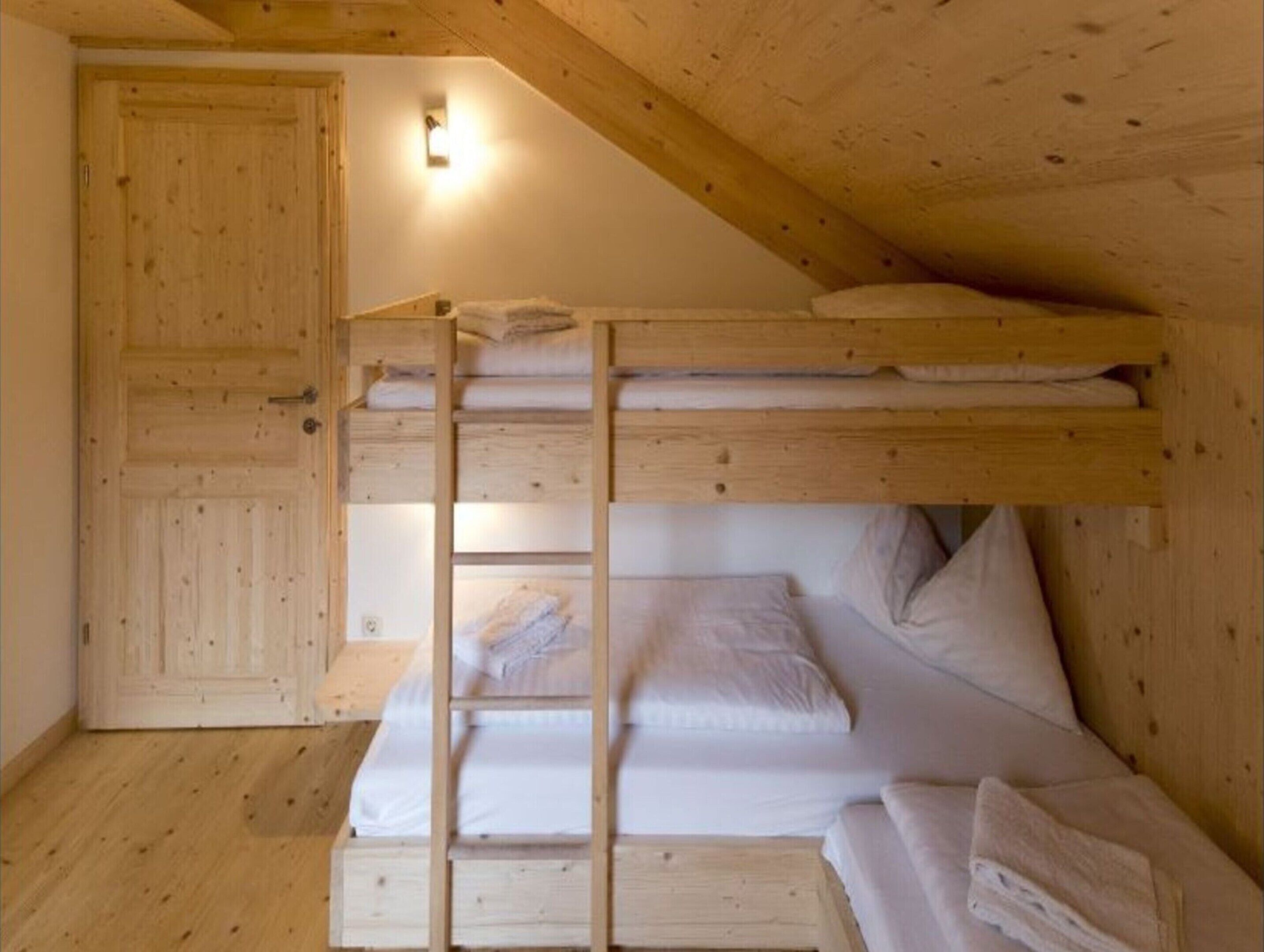 A bunk bed room with wooden walls and a sloped ceiling.
