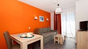 A modern living room with a dining table, sofa, and television. - Stylish Coastal Retreat (Sète)