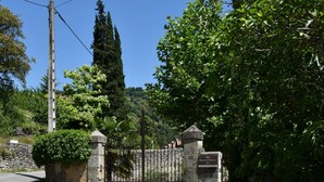 Une entrée fermée par un portail, avec un mur en pierre, un portail en métal et une plaque indiquant le numéro 215.