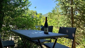 A table with a bottle of wine, surrounded by greenery and trees.