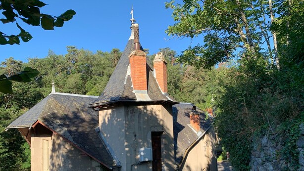 A small stone building with a sloped roof, a chimney, and a small entrance.