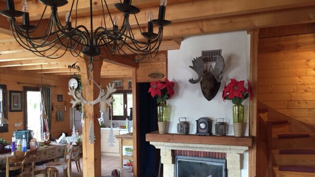 Ein rustikales Interieur mit Kamin, Holzbalken und einer Chandelüster.