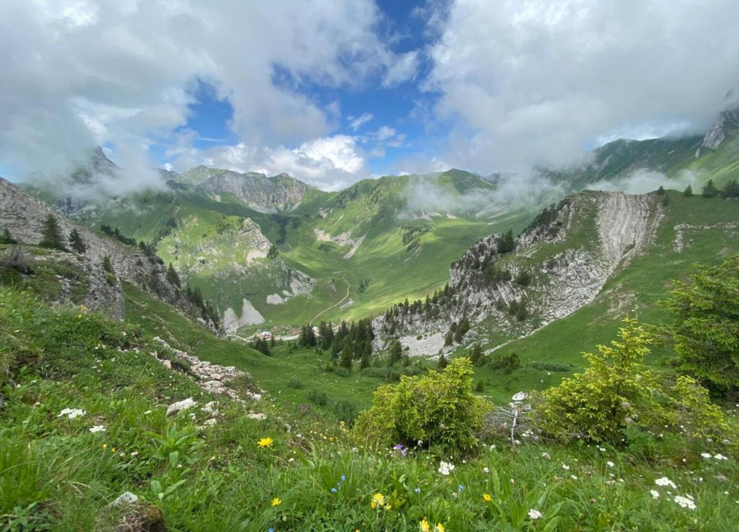 A mountainous landscape with a valley, greenery, and a winding path.