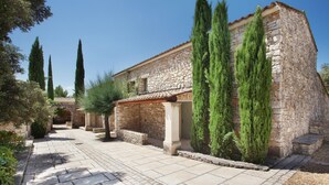 A stone building with a tiled roof, surrounded by greenery and pathways. - Maisonette in Gordes Near Vaucluse Hills (Gordes)