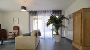 A living room with a sofa, a chair, a large potted plant, a wooden wardrobe, and a radiator. - Holiday Home Near Opal Coast Wierre-effroy (Wierre-Effroy)