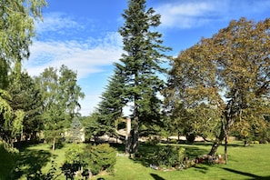 A well-maintained garden with a variety of trees, a lawn, and a small seating area. - Saint-sauveur Hideaway (Saint-Sauveur-Villages)