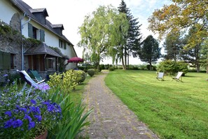 A stone pathway leading to a house with a covered porch, surrounded by a well-maintained lawn and trees. - Saint-sauveur Hideaway (Saint-Sauveur-Villages)