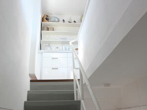 Staircase leads to a spacious interior with a minimalist design and a functional cabinet and shelf.