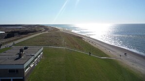 Vista costera con playa, zona verde y un edificio de techo plano.