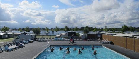 A swimming pool with people swimming and sunbathing.