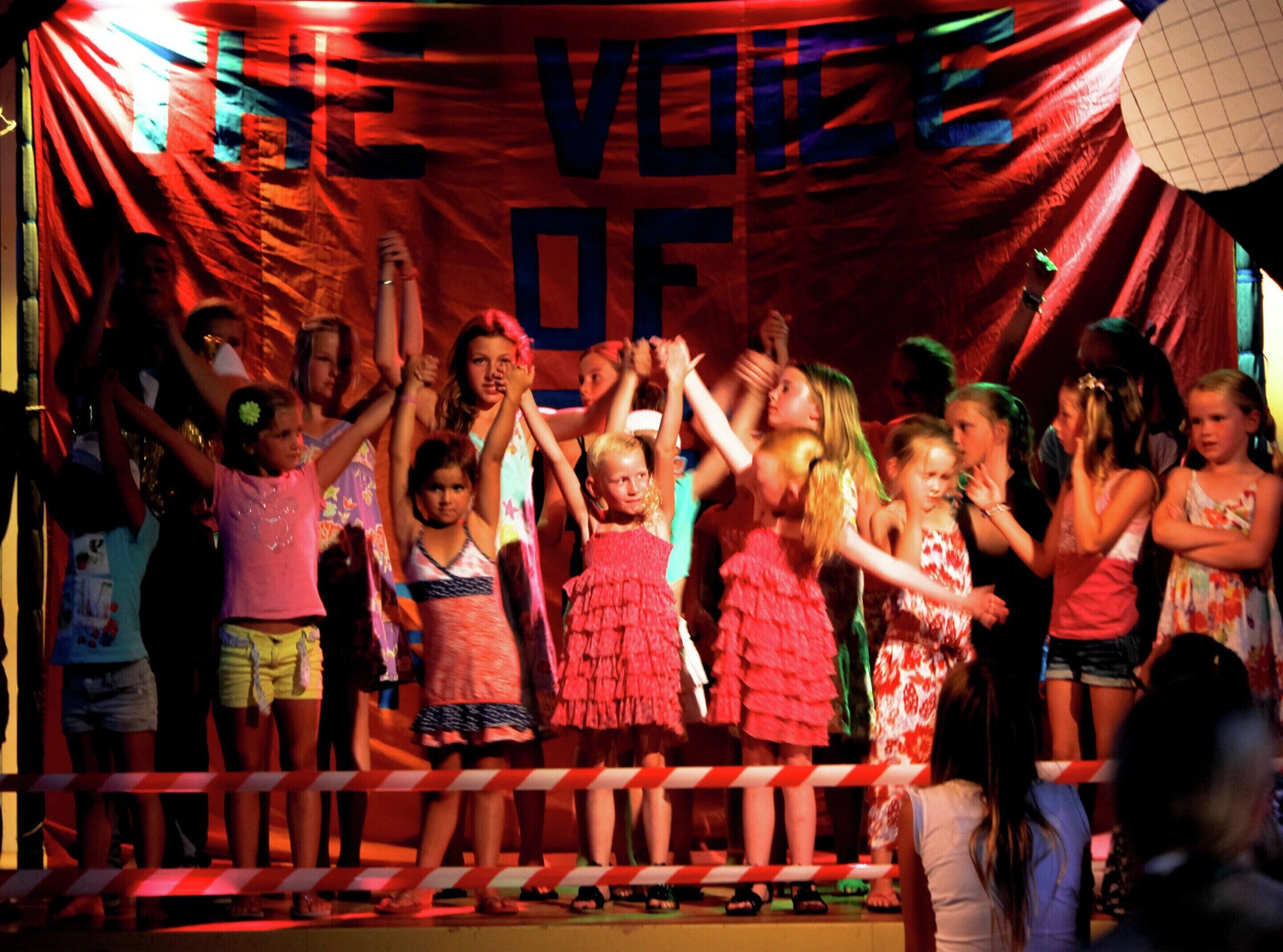 A stage with a banner reading "THE VOICE OF".