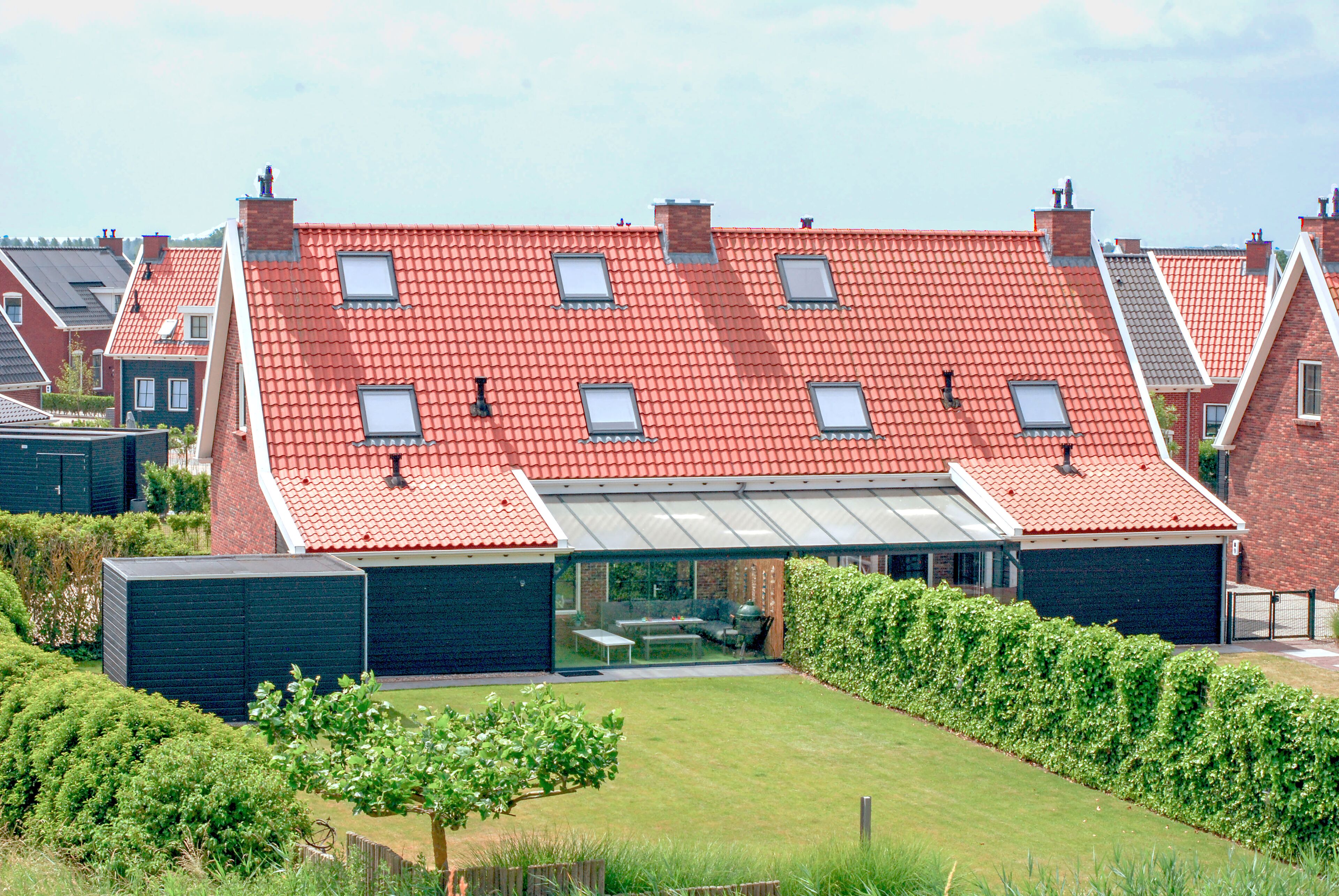 A residential building with a red-tiled roof, multiple windows, and a covered patio area.
