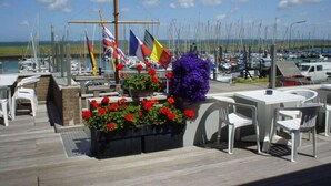 A marina with multiple boats, a flag display, and outdoor seating with flowers. - Holiday Home in Colijnsplaat by the Lake (Colijnsplaat)