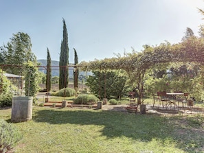 A garden with a pergola, a table and chairs, and a stone planter. - Cottage in Oppede With Poolside Bliss (Oppede)