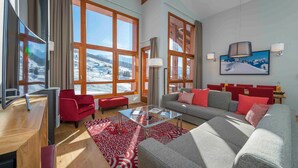 A spacious living area with a large window, a sofa set, a glass coffee table, and a television. - Modern Mountain Base (Bourg-Saint-Maurice)