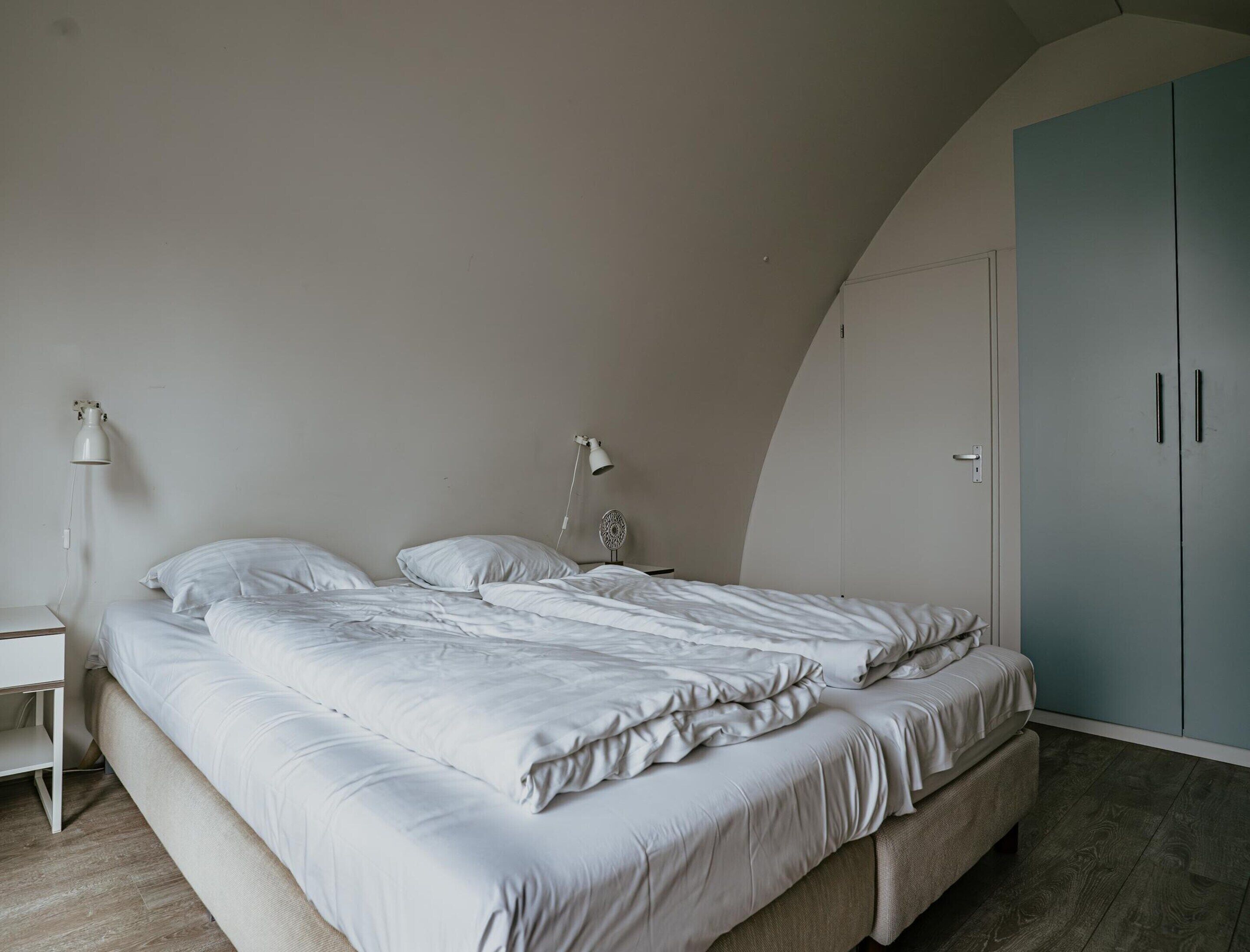 A bedroom with a bed, bedside tables, and a wardrobe.