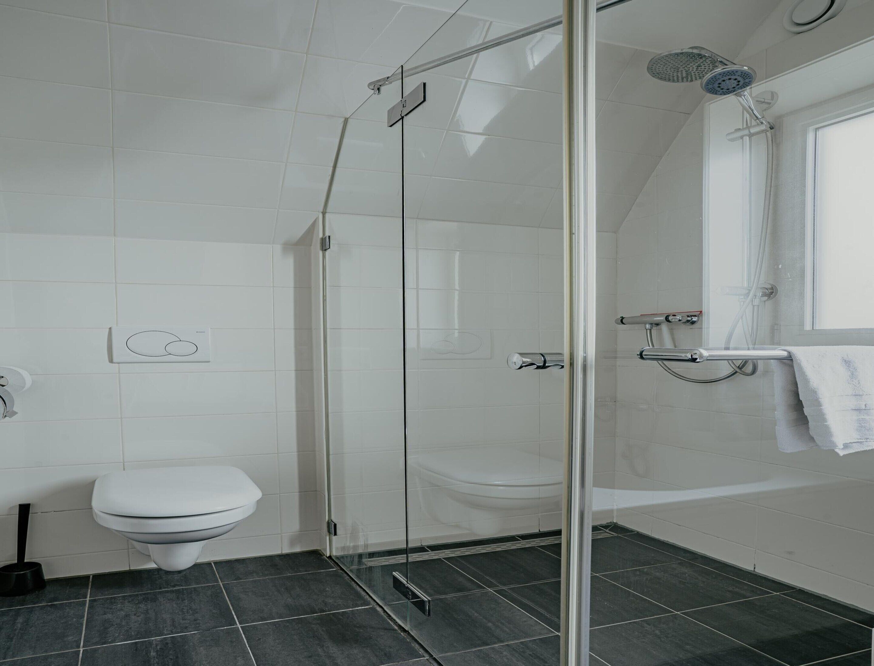 A modern bathroom with a glass-enclosed shower, a toilet, and a bathtub.