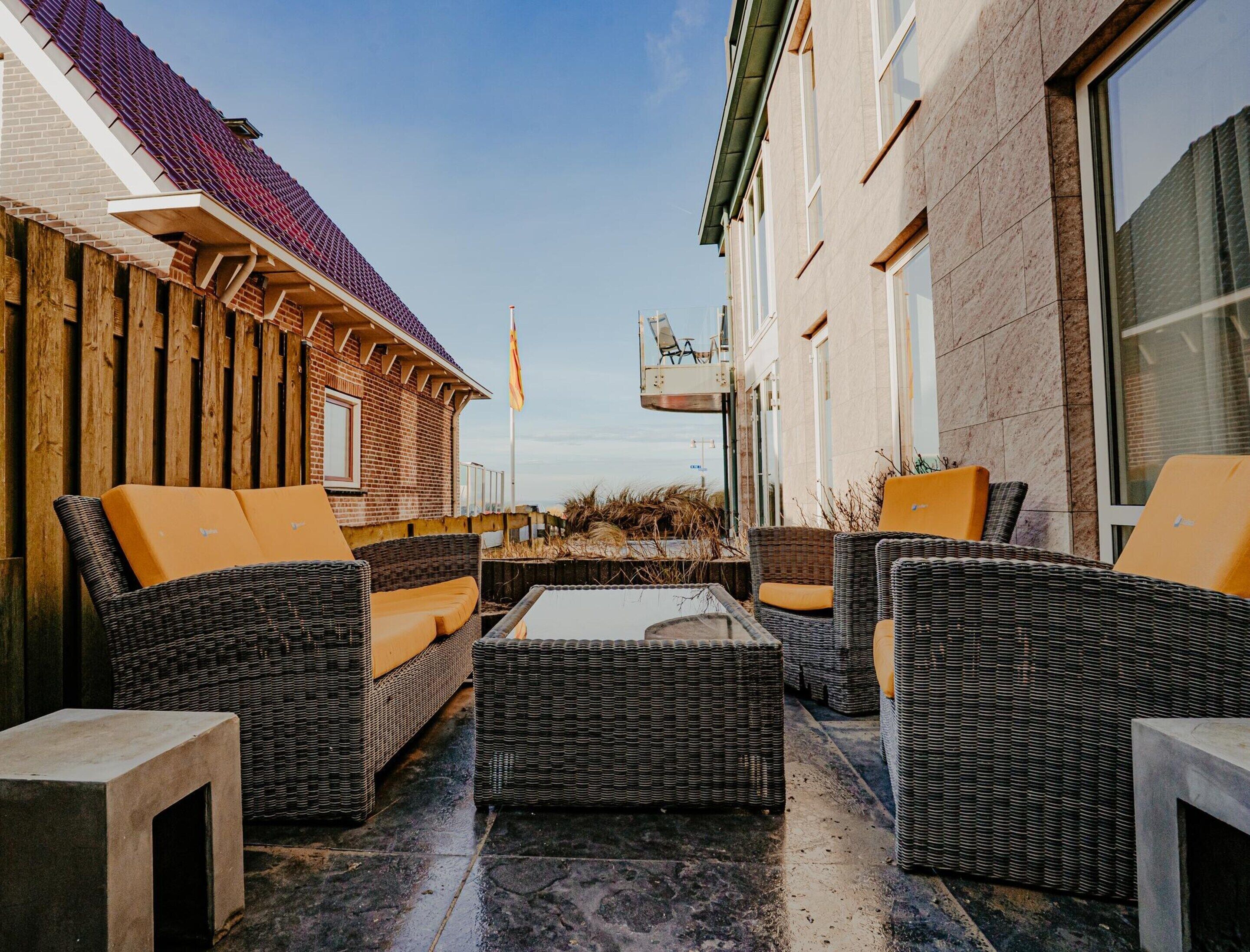 An outdoor seating area with wicker furniture and a tiled floor.