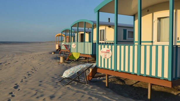 A row of beach huts with a sign indicating 'Vulkanburg' and a number '502'. - Living Van on the Beach With Sea Views ('s-Gravenzande)