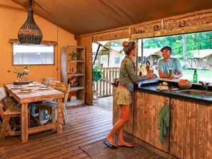 Een rustieke keuken met een houten aanrecht, een hanglamp en een eethoek met een tafel gedekt voor vier personen.